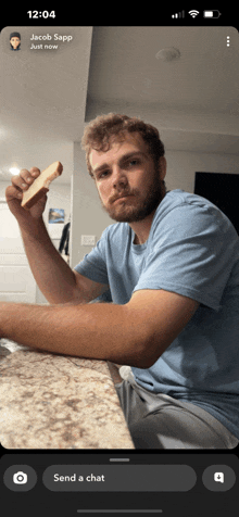 jacob sapp is sitting at a counter eating a sandwich