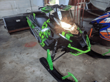 a green and black snowmobile with the word arctic cat on it