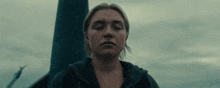 a woman with her eyes closed is standing in front of a pole in the dark .