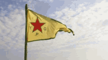 a yellow flag with a red star on it is flying in the wind