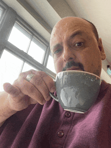 a man with a ring on his finger drinking from a grey cup