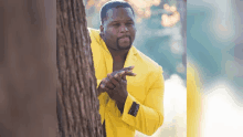 a man in a yellow suit is standing next to a tree