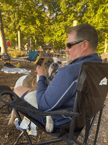 a man sits in a chair holding a dog