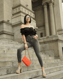 a woman standing on a set of stairs holding a red purse