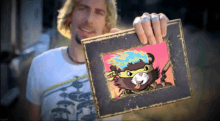 a man is holding a framed picture of a cat with a mask on