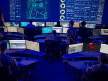 a group of soldiers are sitting in front of a large screen that has a graph on it