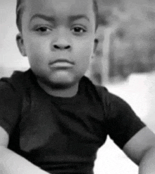 a black and white photo of a young boy wearing a black shirt .