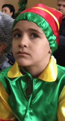 a young boy in a green and yellow costume with a red hat