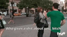 a man in a green shirt is talking to a woman in a striped shirt on a city street .