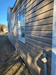 the side of a house with a shadow of a pole on the ground