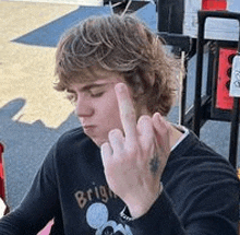 a young man is giving the middle finger while wearing a black shirt .