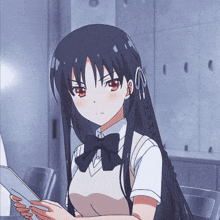 a girl with long black hair is holding a piece of paper in her hand