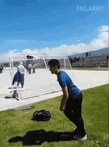 a man in a blue shirt is squatting down in front of a soccer goal with failarmy written in the corner