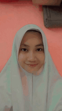 a woman wearing a white hijab and a white shirt smiles for the camera