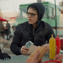 a man sitting at a table with ketchup and mustard bottles and a cell phone that says ' i love you '