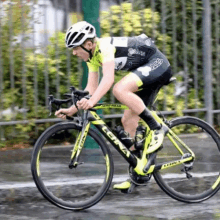 a man wearing a helmet is riding a bicycle on a wet road .