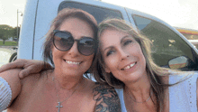 two women standing next to each other in front of a white van