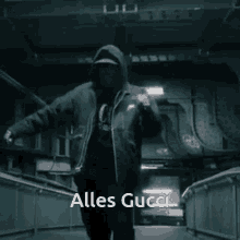 a man in a hooded jacket is dancing with the words alles gucci behind him