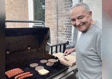 a man is cooking hamburgers and sausages on a grill outside