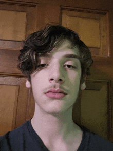 a close up of a young man 's face against a wooden door