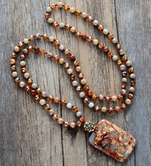 a necklace with beads and a pendant on a wooden surface .