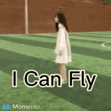 a girl in a white dress is standing on a soccer field with the words " i can fly " above her