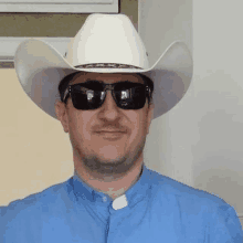 a man is wearing a cowboy hat and sunglasses .