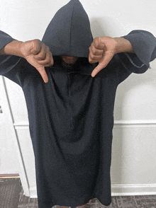 a person wearing a black hoodie giving a thumbs down