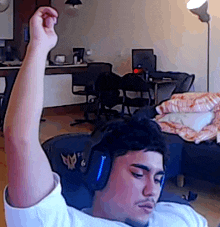 a man wearing headphones is sitting in a chair in a living room with his fist in the air .