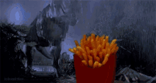 a bucket of french fries is sitting in front of a dinosaur statue .