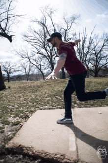 a man throwing a frisbee on a sidewalk in a park