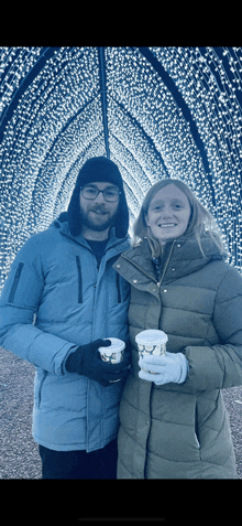 a man and a woman are posing for a picture while holding cups of coffee