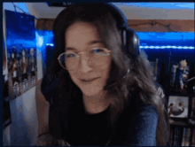 a girl wearing glasses and headphones is smiling in a room