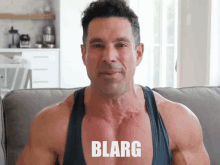 a man sitting on a couch with the words blarg on his chest