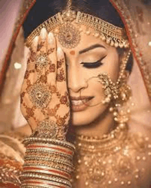 a close up of a bride with a henna tattoo on her hand covering her face .