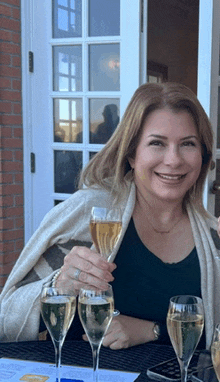 a woman is sitting at a table with three glasses of champagne in front of her