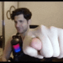 a man is pointing at the camera while holding a remote control in his hand .