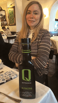 a woman is sitting at a table with a bottle of olivastro