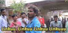 a man in a blue shirt stands in front of a crowd with the words linkuu linkuu linkuu linkuu in yellow