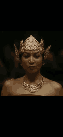 a woman is wearing a gold crown and necklace