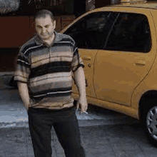 a man is standing in front of a yellow car .