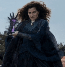 a woman in a witch costume is holding a purple wand .