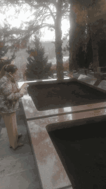 a woman in a leopard print jacket is reading a book in front of a pool