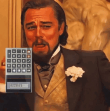 a man in a suit is holding a calculator that says boobies on the screen