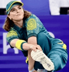 a woman in a blue and yellow uniform is squatting down with her legs crossed