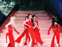 a group of women are dancing on a stage in red dresses