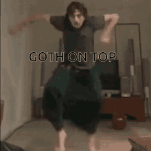 a man is dancing in a living room with the words goth on top written above him .