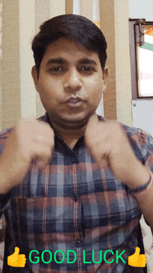 a man in a plaid shirt is giving a thumbs up with the words good luck written above him