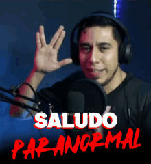 a man wearing headphones waving his hand in front of a microphone with the words saludo paranormal written below him