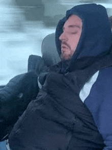 a man is sleeping in a car with a hood on .